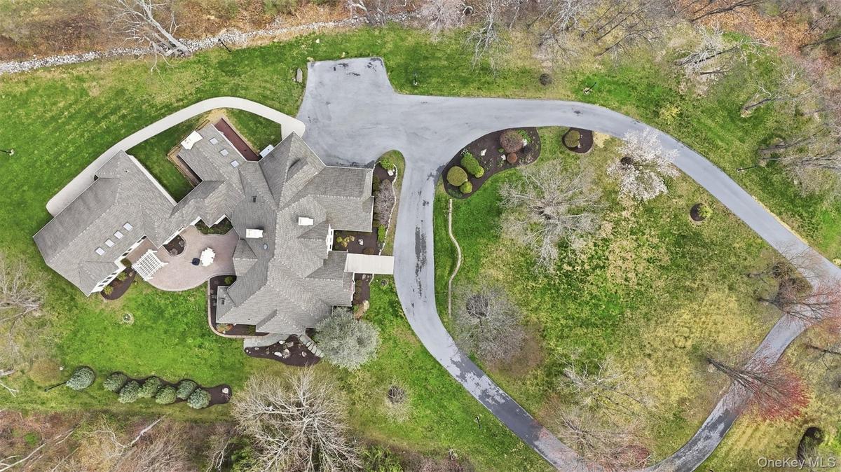 Expansive property with a large driveway, established trees, and a spacious patio area
