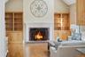 Living area featuring hardwood floors, a brick fireplace with a white mantel, and built-in wooden shelving units