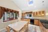 Kitchen featuring vaulted ceilings, a skylight, recessed lighting, wood cabinetry, and dark countertops