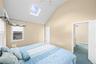 Vaulted ceiling, skylight, wall-mounted ceiling fan, window with blinds, and paneled interior doors