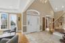 The property features a grand entryway with high ceilings, an elegant staircase with wood banisters, and arched windows
