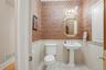 The powder room features a pedestal sink, white toilet, and patterned wallpaper above wainscoting