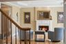 Living room featuring a fireplace with a stone surround and white mantle, warm-toned walls, and hardwood floors