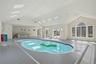 Indoor pool featuring skylights, large windows with arched transoms, and a wet bar area
