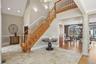 Grand foyer featuring a natural wood staircase with white risers, a vaulted ceiling, and recessed lighting