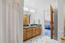 Bathroom featuring a double vanity with a green countertop, wood cabinetry, and a patterned tile floor