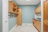 Utility room with light wood cabinetry, shelving, a countertop, and tiled flooring