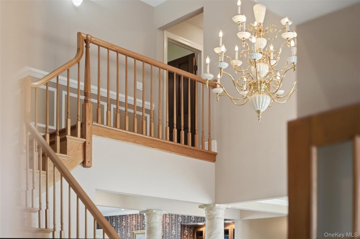 Grand entryway featuring a detailed chandelier, a wooden staircase, and decorative wall molding