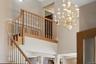 Grand entryway featuring a detailed chandelier, a wooden staircase, and decorative wall molding