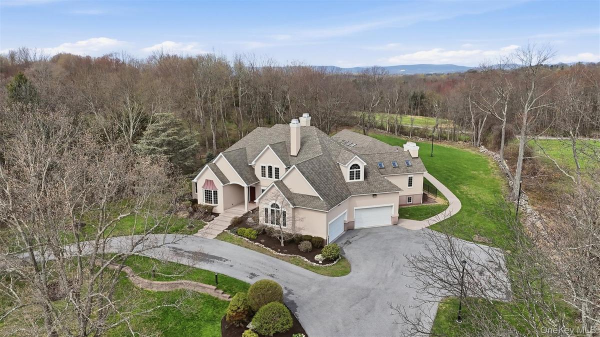 The property features an extensive driveway, a well-maintained lawn, and mature trees