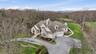 The property features an extensive driveway, a well-maintained lawn, and mature trees