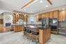 Spacious kitchen featuring extensive cabinetry, an island with a dark countertop, a stainless steel refrigerator, and integrated double ovens