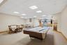 Spacious recreation room featuring carpeted flooring, recessed lighting, and a built-in entertainment area with light blue and natural wood cabinetry