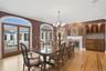 This dining area features hardwood floors, a decorative fireplace, and a built-in wet bar with wood cabinetry and a tiled backsplash