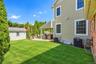 Expansive green lawn with a paver patio featuring a covered outdoor patio, a storage shed, and mature privacy plantings