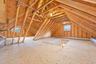 Open attic space with exposed wood rafters, plywood subflooring, and two operable windows