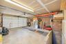 2 car garage, Concrete flooring, exposed brick wall, overhead lighting, segmented garage door with windows, and an overhead storage rack
