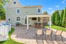 Expansive paver patio with covered outdoor bar, built-in entertainment, and a manicured lawn