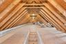 Steps to full attic ,Exposed wood rafters, plywood flooring, and ceiling-mounted lighting fixtures