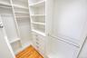 Custom closet system featuring white shelving, multiple hanging rods, and built-in drawers with brushed nickel hardware