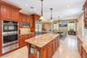 Kitchen featuring wood cabinetry, stainless steel appliances, a large center island with a sink, and granite countertops