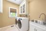 Laundry area featuring a utility sink with a pull-down faucet, white cabinetry with glass inserts, and tiled flooring