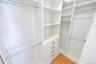 Custom closet system featuring multiple hanging rods, built-in shelving, integrated drawers with brushed nickel hardware, and wood-finish flooring