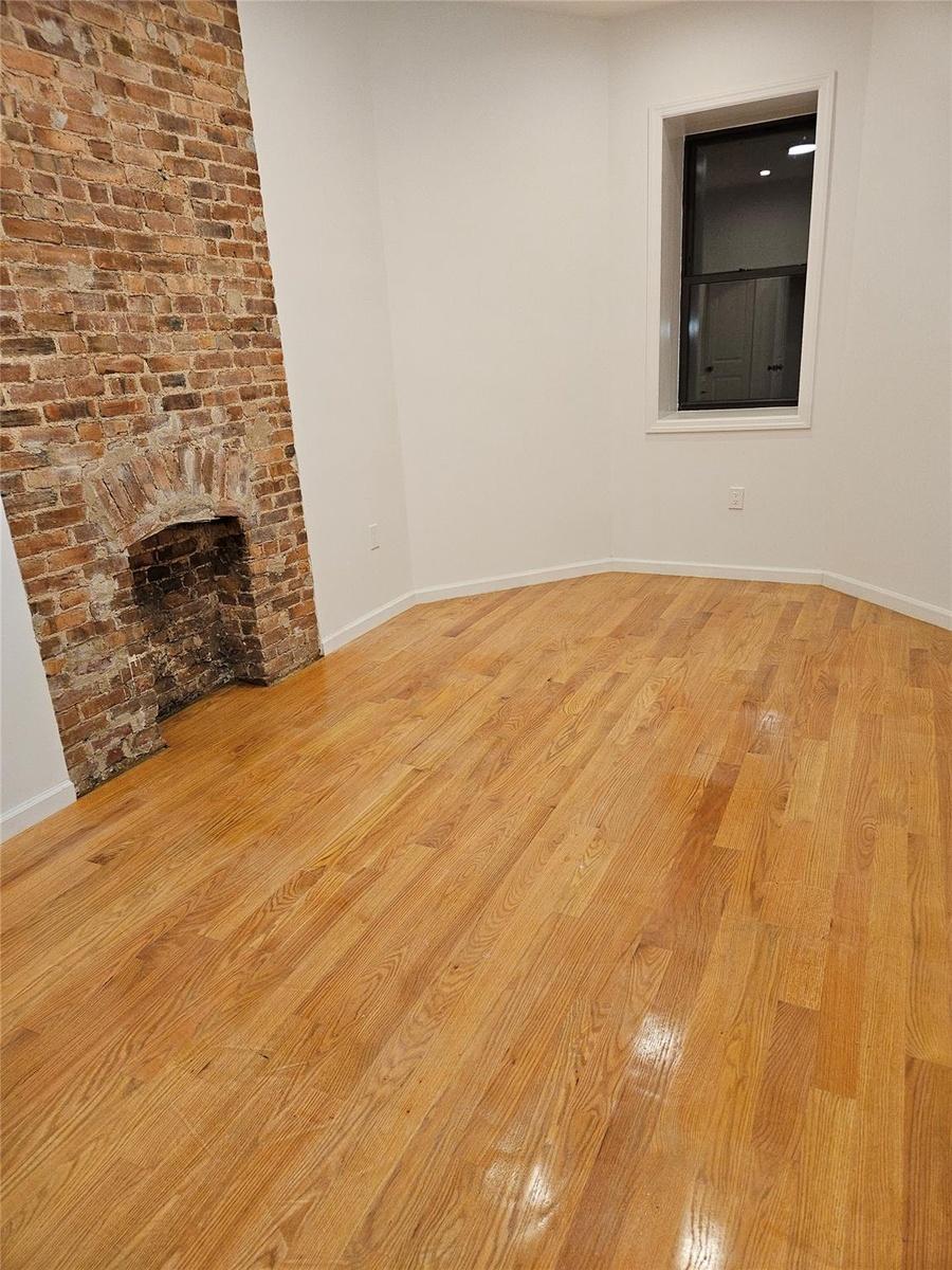 Unfurnished living room with a fireplace, baseboards, and light wood finished floors