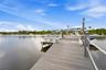 Waterfront property featuring a wood-composite dock, built-in bench seating, and boat lift