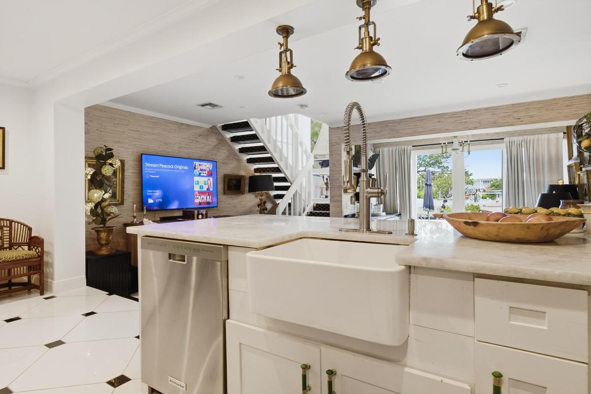 Kitchen island featuring a farmhouse sink, stainless steel dishwasher, and brass pendant lighting