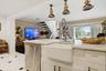 Kitchen island featuring a farmhouse sink, stainless steel dishwasher, and brass pendant lighting