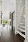 Dark wood-finish flooring, white paneled walls, exposed beam ceiling, built-in shelving, white staircase