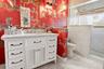 White vanity with a stone countertop, dual undermount sinks, and a decorative gold-toned mirror