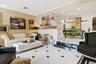 Open-concept living area with large-format floor tiling and wall sconces, featuring a kitchen peninsula with pendant lighting and a dining area