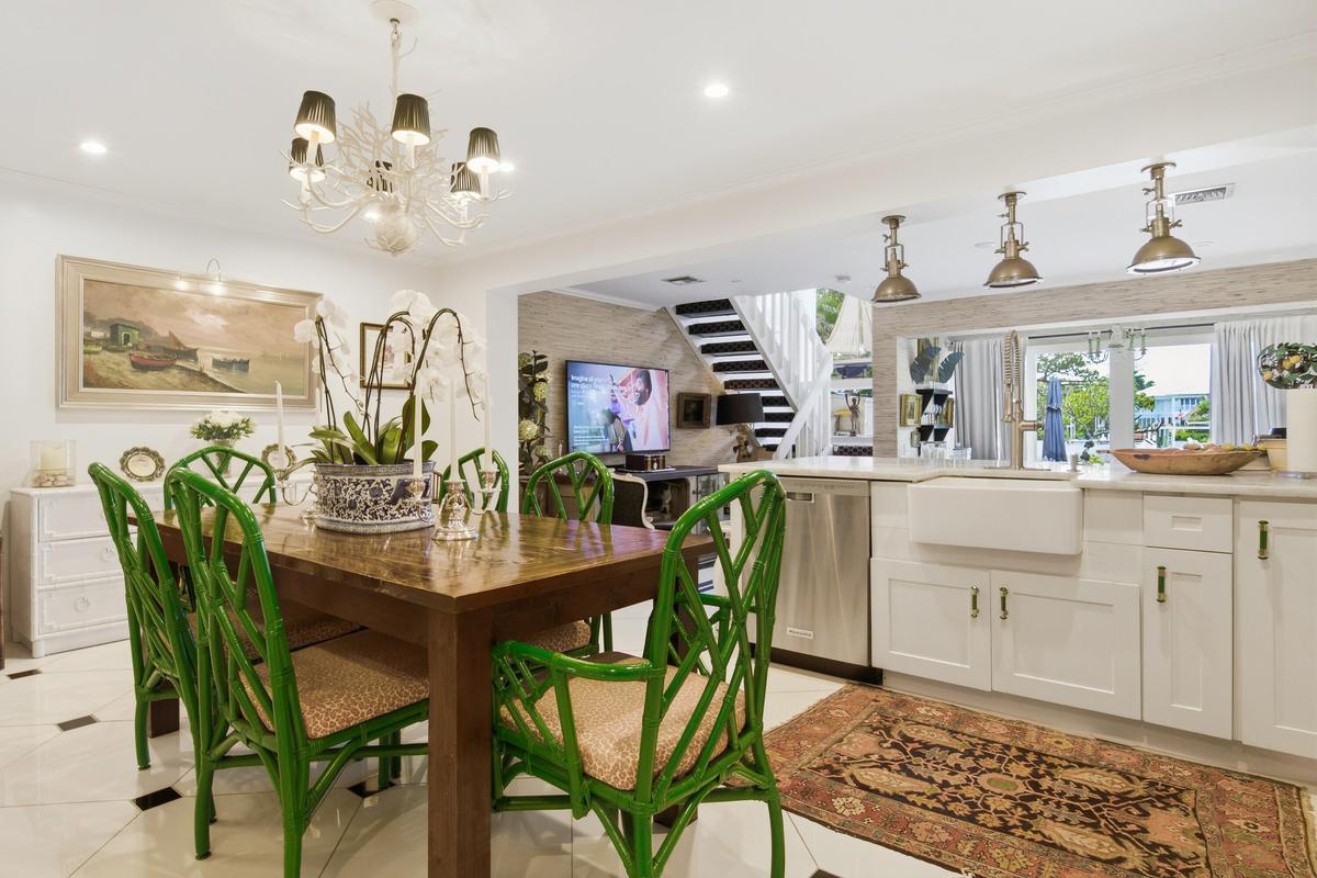 Open-concept living space featuring a dining area with chandelier, a kitchen with white cabinetry and an apron-front sink, and integrated stainless st