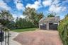 Two-car detached garage with overhead doors, brick-paved driveway, and a manicured lawn area