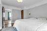 Recessed ceiling light fixture, wall-mounted sconce, wood-finish flooring, and a paneled wood door
