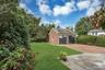Brick garage with two carriage-style doors, a natural stone patio, and a brick paver driveway