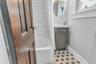Subway tile bath surround, white tub, gray vanity with integrated sink, patterned mosaic floor tile, and an oval mirror