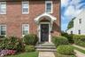 Red brick exterior with white trim windows and a dark panel front door, brick walkway and bluestone steps