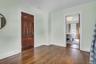 Hardwood flooring, painted walls, solid panel interior door, and a cased opening