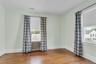 Hardwood flooring, two windows, radiator, and white trim