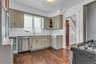 Kitchen featuring wood-finish flooring, white subway tile backsplash, light-colored cabinetry, stainless steel dishwasher, and a window above the sink