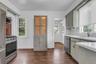 Stainless steel appliances, white subway tile backsplash, white countertops, built-in cabinetry, and wood-finish flooring