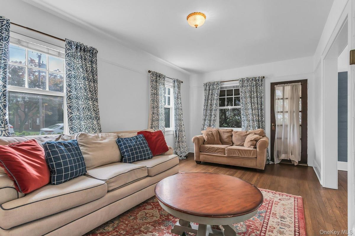 Hardwood flooring, multiple windows providing natural light, white wall finishes, and a classic ceiling fixture