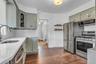 Kitchen featuring stainless steel appliances, wood-finish flooring, white countertops, subway tile backsplash, and light-toned cabinetry