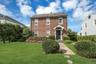 Brick exterior with white window trim, covered entry, and dark-paneled front door