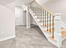Lower level staircase featuring wood treads, black iron balusters, a natural wood handrail, and white risers.