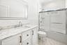 Second floor bath with white vanity with and integrated sink, complemented by stone-finish countertop