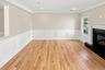 Family Room - hardwood flooring, crown molding, wainscoting, recessed lighting, and fireplace with a mantel.